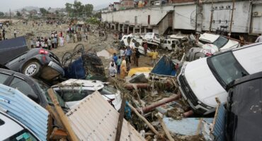 Residents look at damaged vehicles after flash flood and landslide triggered by heavy rains wreaked havoc at Rajouri district in India's Jammu region on July 19, 2026. (Photo by Mir Imran / AFP)