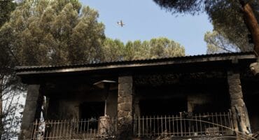 A Canadair firefighting aircraft flies over a burned house following a devastating wildfire in Pelayos de la Presa, 65 kilometers west of Madrid, on July 26, 2026.