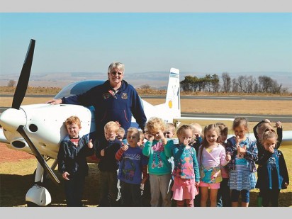Dale de Klerk, owner of Alpi Aviation also providing pilot training at FAKR, and Rabbedoe Nursery School children.