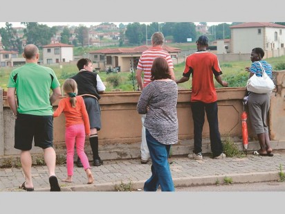 Omstanders by die brug in Jonesstraat kyk of hulle die dertienjarige seun kan sien.