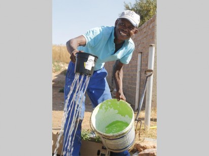 Lebo Motswere shows his excitement for being able to water the plants they received from President Hyper for the park.