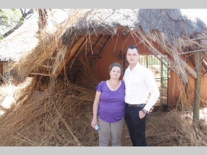 Jenny Theron, eienares van Jenny's Pub en Rainhard le Grange by die oorblyfsels van die grasdak.