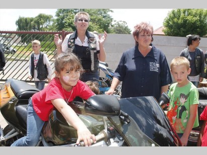 Jaydene Hattingh geniet dit om op die ysterperd te sit. Agter van links is Erica Fourie van die Draconians motorfietsklub, Estelle Opperman van Mug & Tree en Brandon Neveling.
