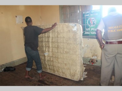 An alleged sex worker lifting up her mattress for the police to inspect.