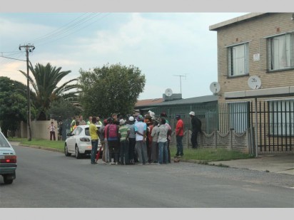 A group of angry Munsieville employees demand their outstanding pay outside the home of their employer.