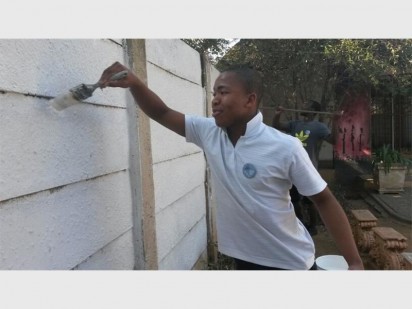 Itumeleng Monyai wat deur Ripple Reading 'n beurs by Jeppe Boys High verower het en tans by UJ swot, verf die muur.