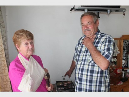 Met die knopkierie in haar hand en 'n slinger om haar regterarm vertel Rosa en Johan van der Walt oor toe hulle langs hulle bed verras is. Hier wys Johan, wat wys hoe hy verwurg is en waar die koeël hulle slaapkamer muur getref het.