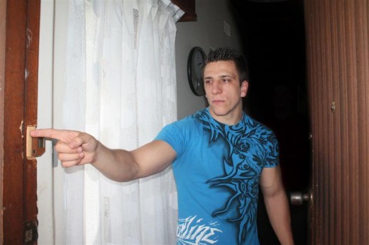 Mikael Cope shows where four men gained entry through the front door by using a crowbar.