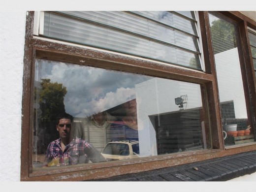 Kristopher, Kathy and Chantelle Cope look at the kitchen window where four men gained entry to their home.