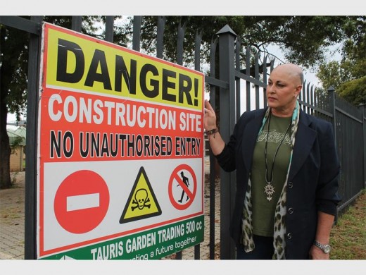 Amanda de Lange, 'n Vryheidsfront Plus raadslid vir Mogale City voor die konstruksieborde wat wys dat Bob van Reenen Stadion nog onder konstruksie is.