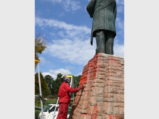 Lucky Khoza is hard besig om die verf op die voetend van Paul Kruger te verwyder.