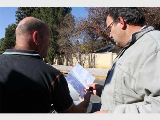 Shaun Dercksen hands Tjaart Steenkamp the electricity invoice.