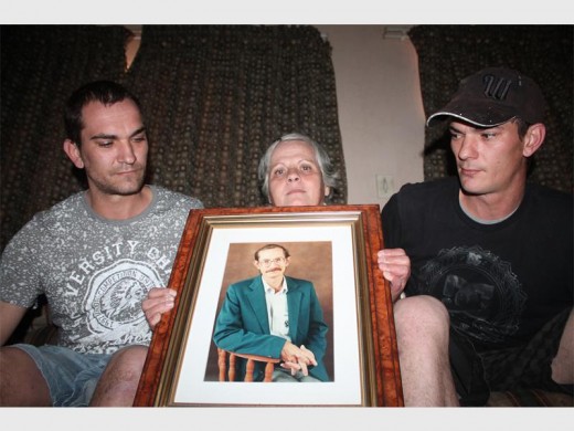 Johan, Marina en Pieter van Loggerenberg sit hier met 'n foto van hul pa en man nadat hy in 'n vermeende padwoedevoorval gesterf het.