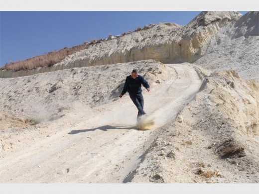 DA councillor De Waal Venter kicks dust in the air to show how easily the wind could blow it away.