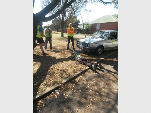 Block Watch patrollers wait for the police to pick up the burglar, seen lying on the ground.