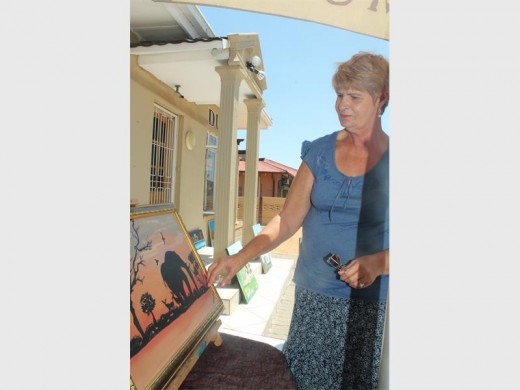 Martie Hughes spog met kunswerke by haar uitstalling in haar tuin.
