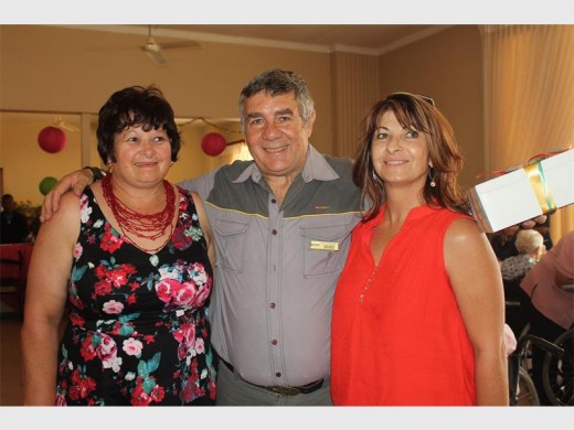 Amande Bekker en Letisha Botha handig 'n geskenkpakkie aan Môreglans Tehuis se Fanie Meyer.