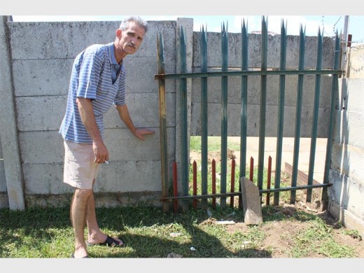 Hennie Coetzee dui aan hoe hoog die water opgestoot het voordat die betonmuur ingegee het en die water deurgelaat het. Die gesin het nou tydelike pelisade teen die muur opgesit.
