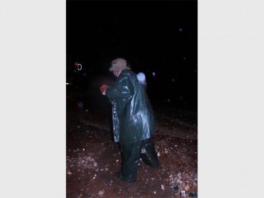A member of the Sector 3 Community Policing Forum clearing the rocks and dirt from Van Riebeeck Road in the poring rain.