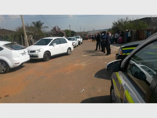 Residents grouped outside the shack where two men were found murdered yesterday.