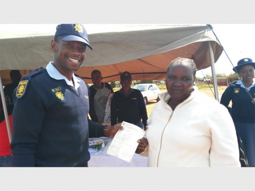 Constable Lucky Matome hands over an affidavit to Elizabeth Ndebele who needed it to apply for an ID.