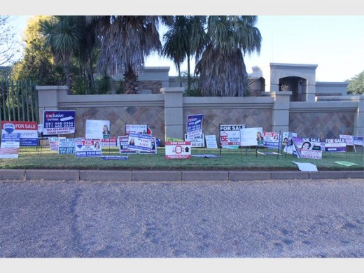 A resident's front lawn decorated with numerous for sale boards.