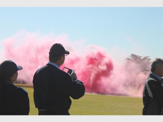 A pink smoke signal displayed on the rugby field as the pupils sit amazed at the bright colour.
