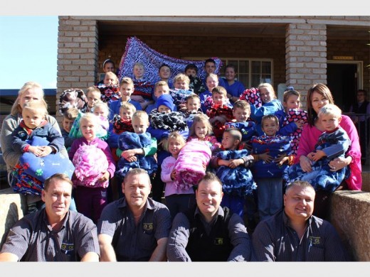 Mapogo a Mathamaga-sekuriteit se verteenwoordigers by die skool se 30 leerlinge nadat hulle elkeen 'n kombers ontvang het.