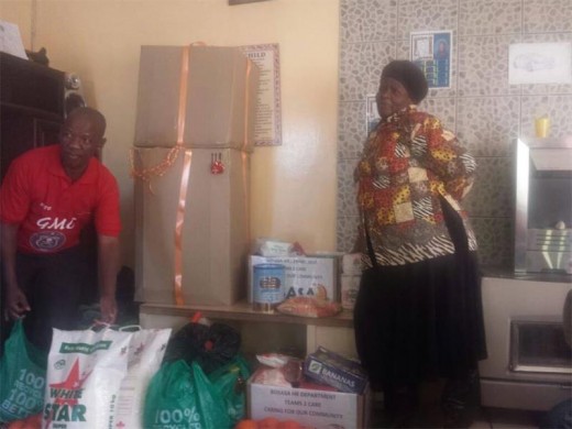 Kamohelo Montsi, branch deputy chairperson, handing over food parcels and clothes to Mrs Malatjie.