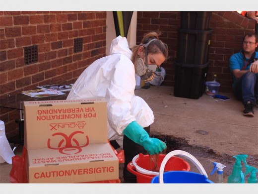 Shalene Botha, crime scene clean-up crew member cleaning a staged crime scene at a demonstration.