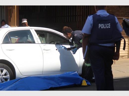 A forensic investigator collecting fingerprint evidence from the vehicle in which a man was fatally shot at noon today.