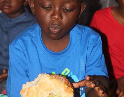 Brandon Pfano, of Honeyfield Daycare, needs two hands to hold the Spur beef burger at the daycare's birthday bash.