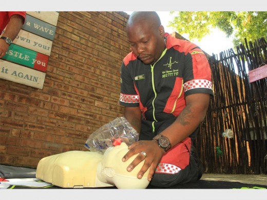 Tay Cikhethe, a basic life support paramedic, places an eye/ face splash protection device over a mannequin's mouth to demonstrate how it should be used during CPR.