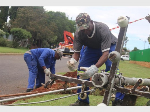 Bandile Masimola, a Mogale City Municipality infrastructure employee removes one of the electricity cables from the collapsed electricity pole. In the background Oupatjie Rammekwa digs a hole for the new pole.
