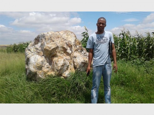 Swaneville Massacre Committee Chairperson, Johannes Kodisang, next to the rock that families of the deceased use as a monument.