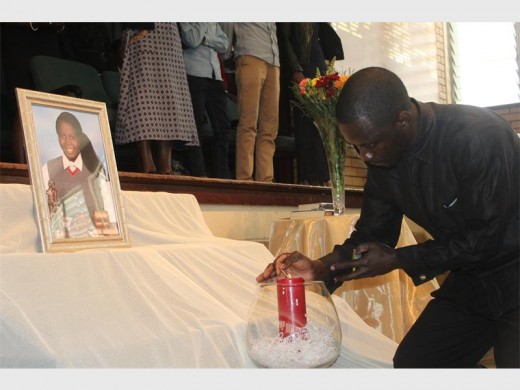 Mr Ngomba lighting a candle during the minute's silence.