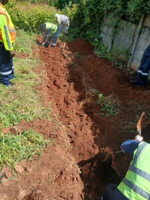 Municipal workers at a trench on the sidewalk repairing electricity cables.