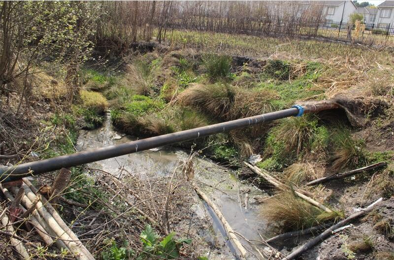 A persistent sewage leak into a local watercourse has been halted following the installation of a steel pipe, but questions remain over who carried out the repair.