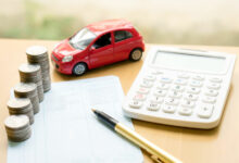 Coins stack in columns on saving book and car on finance concept