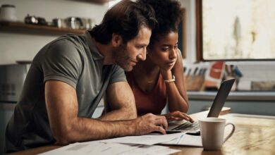 Couple with a laptop doing finance paper work, paying debt insurance loans or online ebanking together at home. Two serious people planning and looking at financial document, bills rate for mortgage