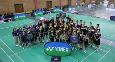 A group of people posing for a photo in a badminton court.