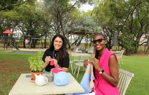 Angela Barcellos from Brazil sits and knits with Lindo Mbalati from South Africa.