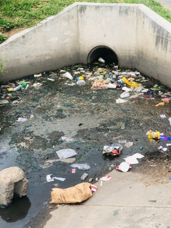 A storm water drain on Winnie Mandela Drive is blocked with litter, and a man was caught in the act of adding to it. When asked why, he said the drain was dirty anyway. The incident raises questions about why people continue to litter, even when bins are available nearby.