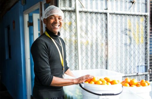 A volunteer smiles by a bucket of oranges that will help FoodForward SA feed the hungry. Photo: Supplied