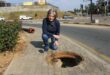 Tracy Kensey kneels beside an uncovered stormwater drain on the pedestrian walkway at the corner of Rivonia and Leeuwkop roads in Sunninghill as she raises concerns about the potential danger it poses to the public on 28 June, 2026. Photo: Ayanda Ntshingila