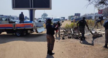 Metro police officers remove structures and belongings during an operation to clear an illegal occupation near Tiger Wheel & Tyre on Winnie Mandela Drive. Photo: Supplied