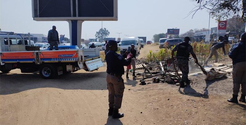 Metro police officers remove structures and belongings during an operation to clear an illegal occupation near Tiger Wheel & Tyre on Winnie Mandela Drive. Photo: Supplied