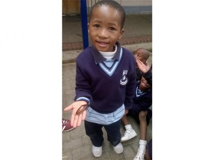 A pupil looking chuffed with himself while holding an insect.