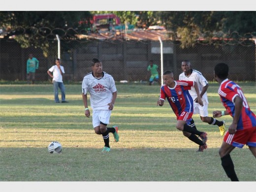 Taks's Llewelin Brummer (centre) challenges for the ball.