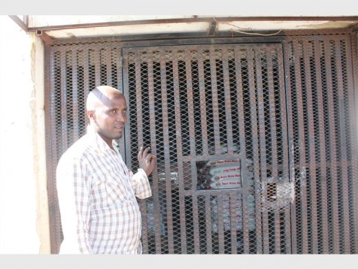 Although Ethiopian shop owner Daniel Ersamo returned to the informal settlement to reopen his shop, he remains very wary of looters. For that reasonhe no longer allows customers to enter his shop. He is now using a small opening in the security gate to pass items through to them, as he believes this will make it difficult for thieves to get his goods out of the shop.